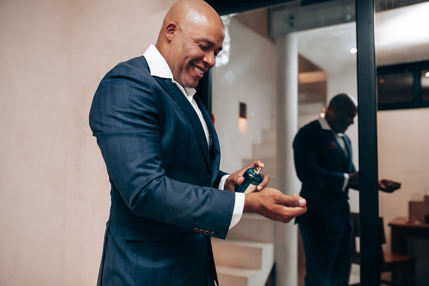 Professional in a dark suit checks messages on smartphone while walking through an office hallway.