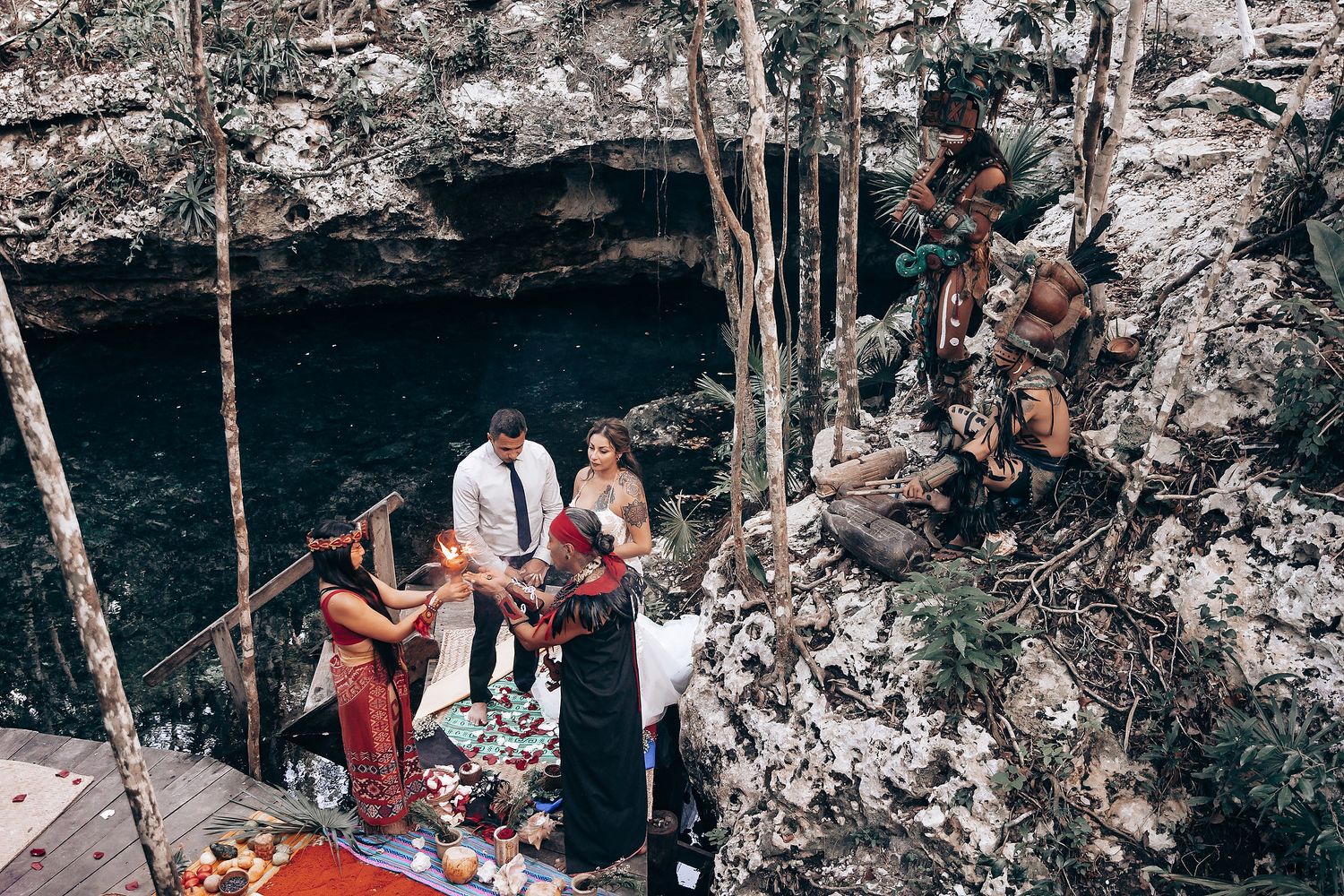 A romantic wedding ceremony takes place in a stunning natural cenote cave setting with rocky walls and natural light.