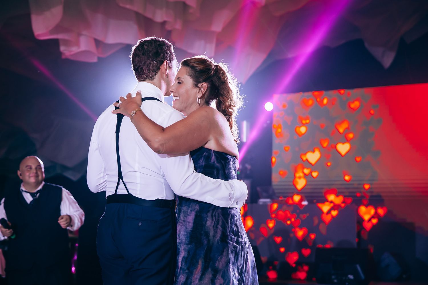 Couples dancing at a wedding reception with dramatic purple and red lighting effects.