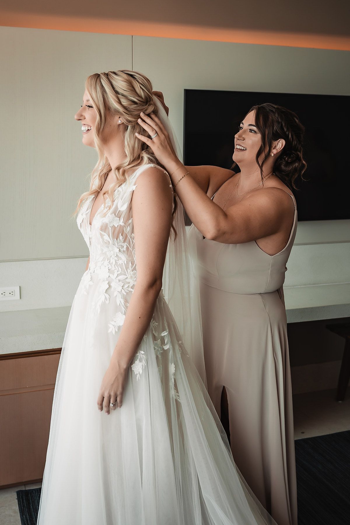 Bridesmaids in neutral dresses share emotional moments while getting ready for a wedding ceremony.