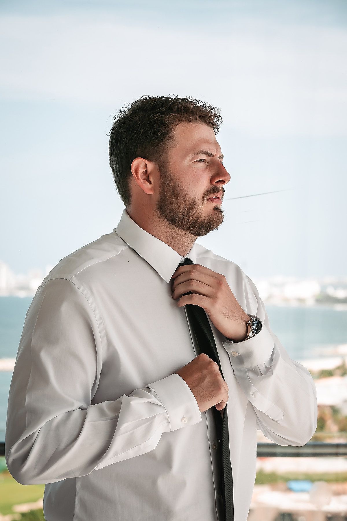 Series of shots showing someone adjusting a black tie against a white dress shirt.