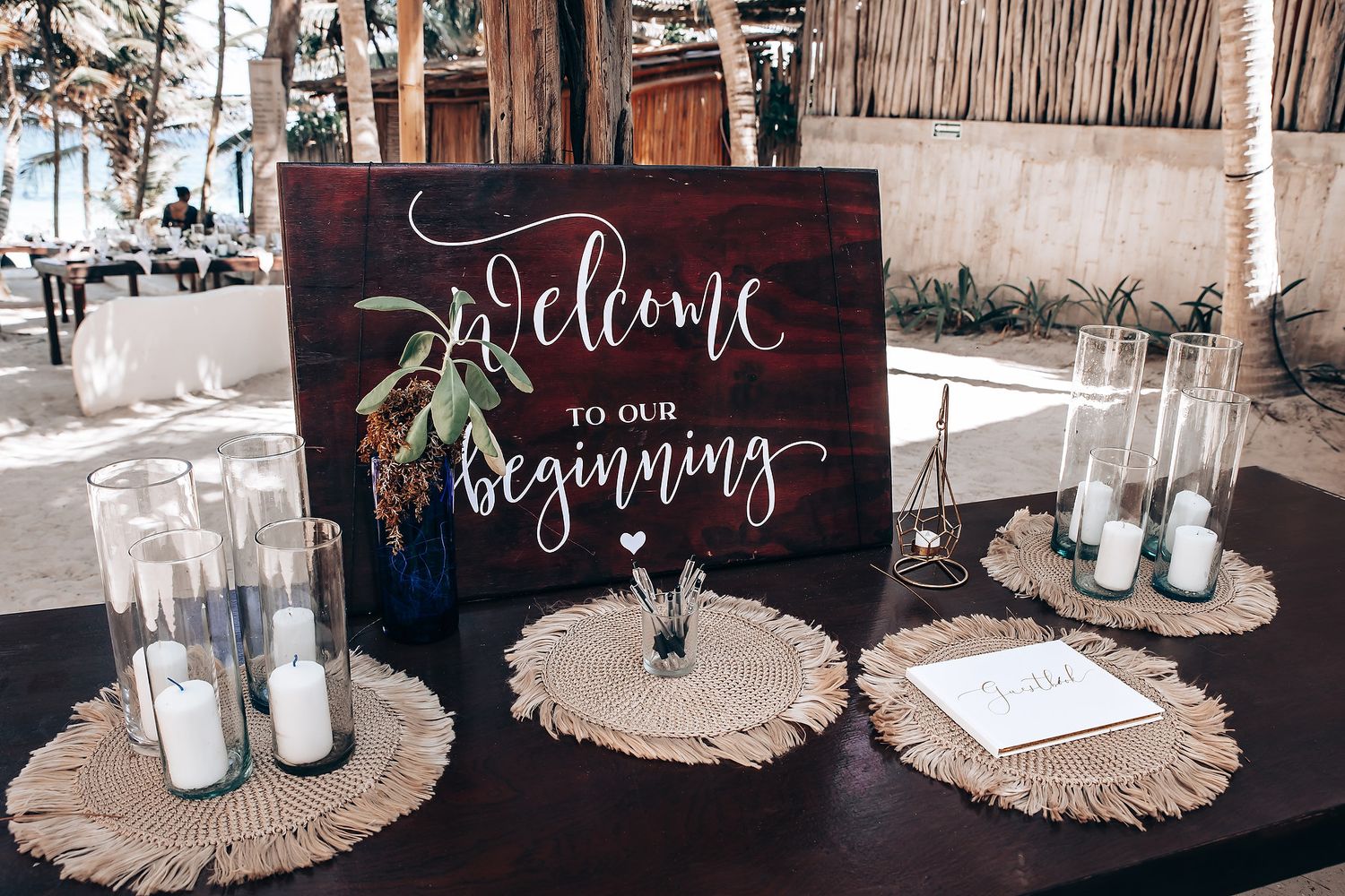 Wedding reception welcome signs and decor displayed on rustic wooden tables with candles.