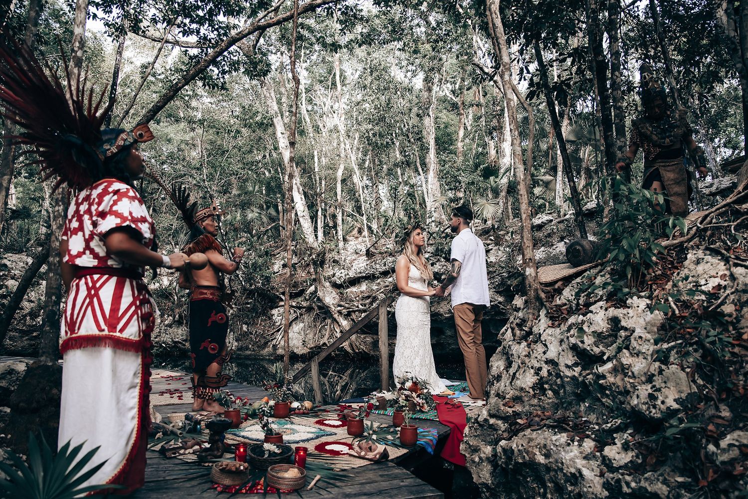 Wooded outdoor gathering space with red and white decorative elements among trees.