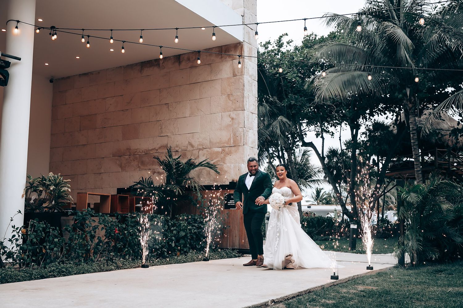 Modern wedding venue exterior with white columns and palm trees.