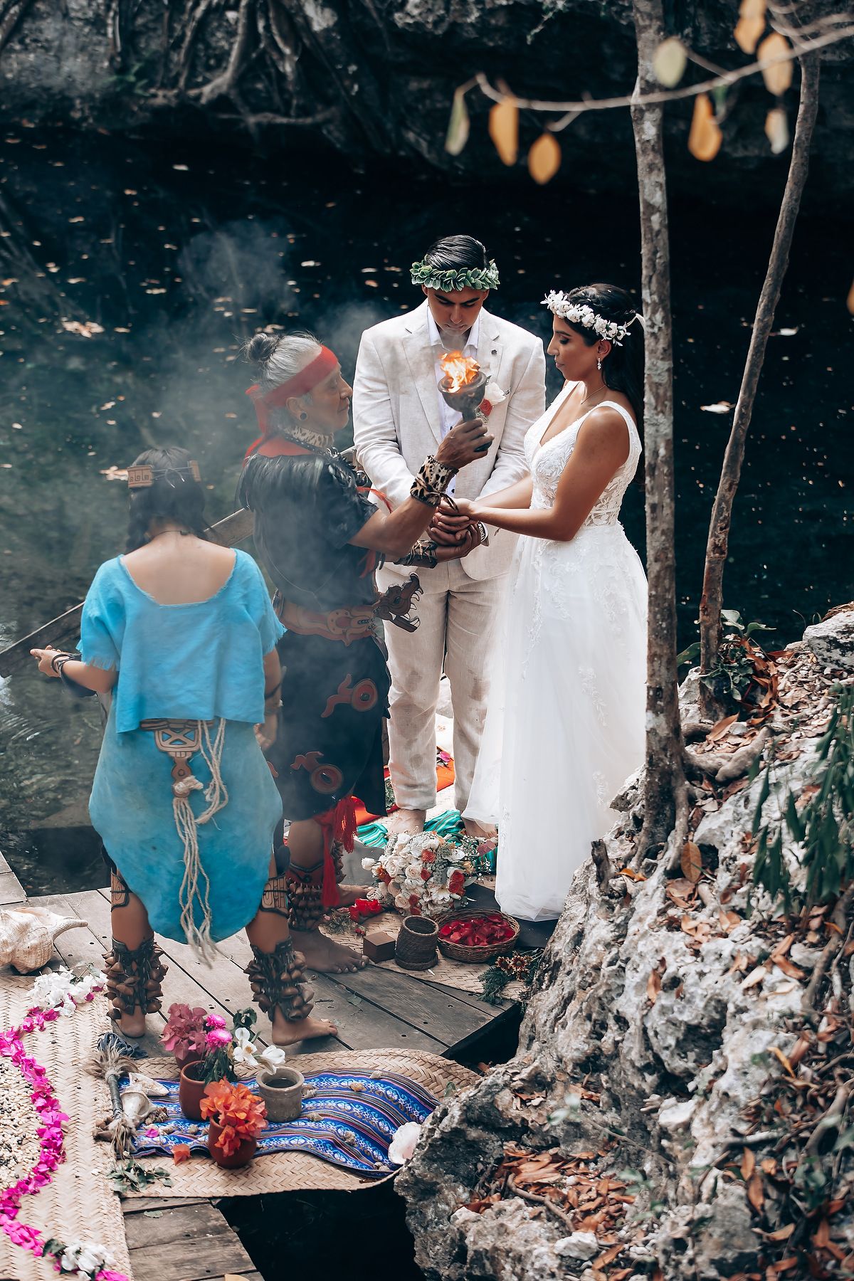 A traditional wedding ceremony takes place outdoors with floral decorations and smoke elements creating a mystical atmosphere.