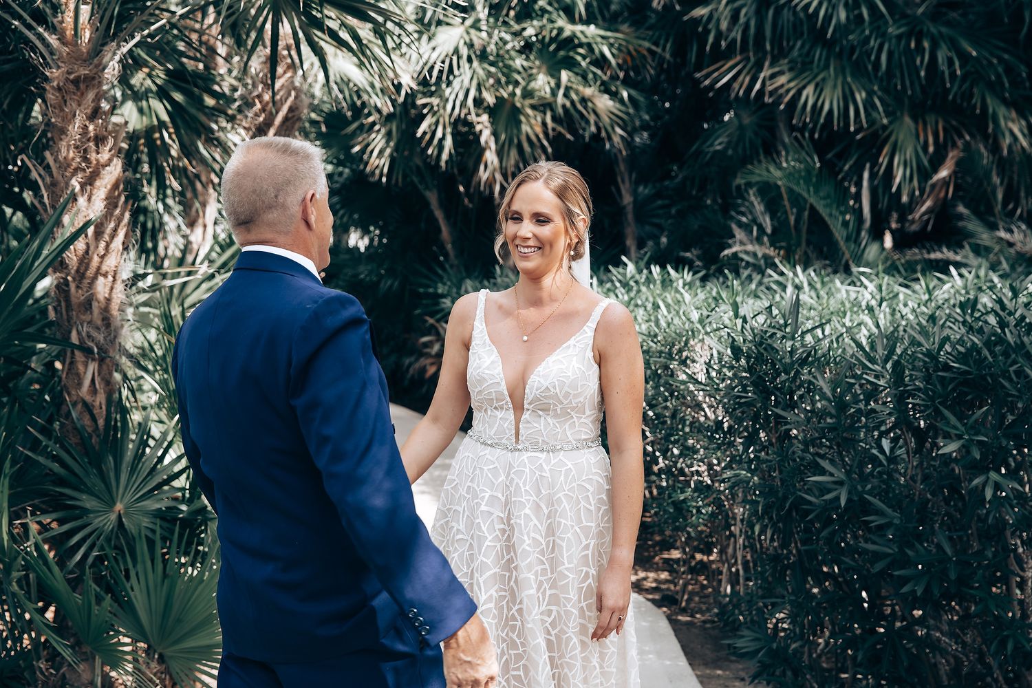 A bride and groom embrace in a lush, tropical garden setting.