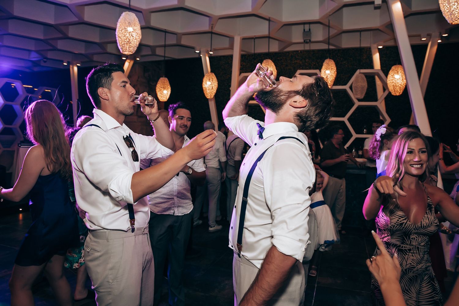 Guests dancing and celebrating at a wedding reception with dramatic purple lighting.