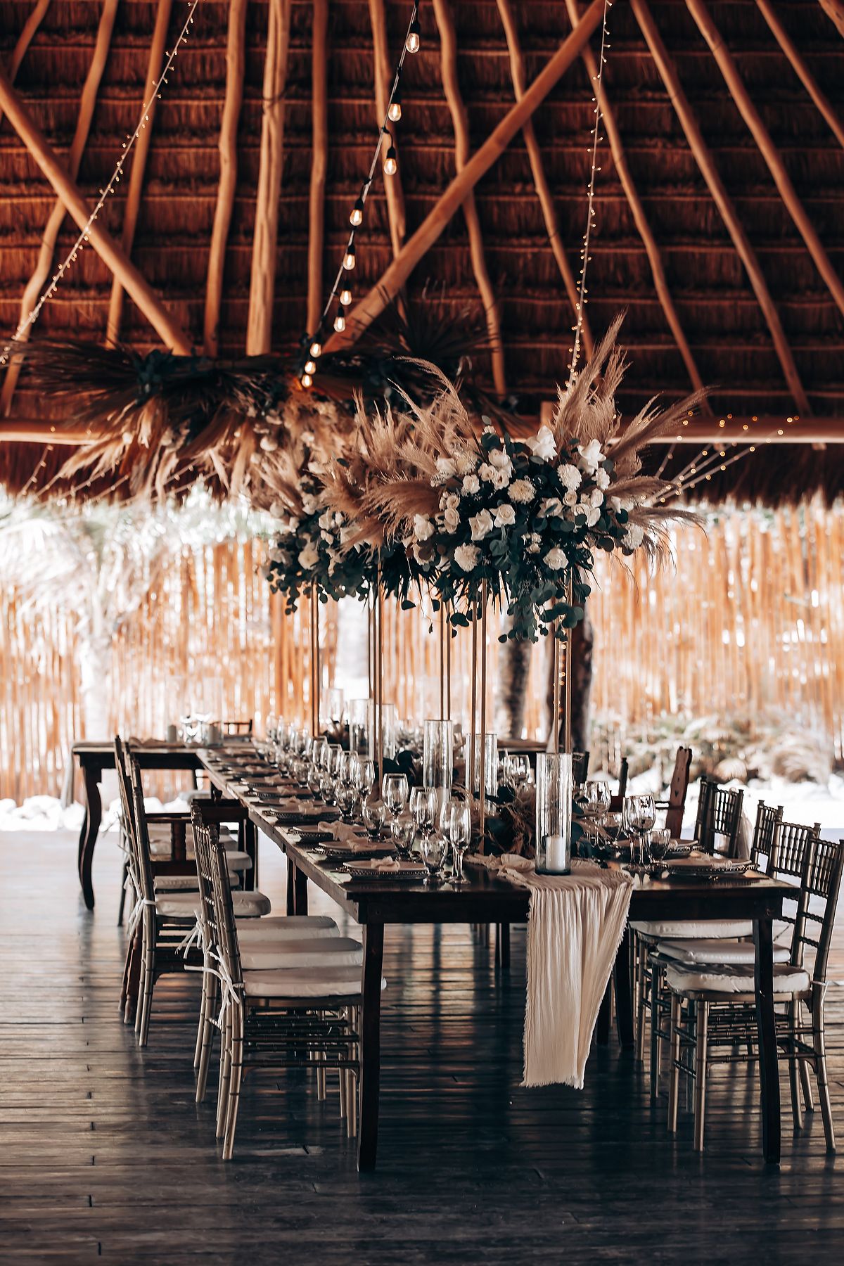 Long rustic barn reception venue with elegant chandeliers and table settings creating a romantic wedding atmosphere.
