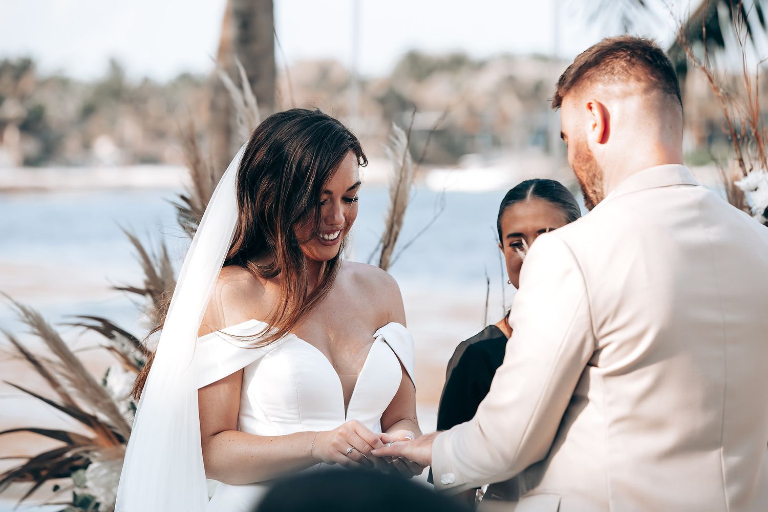 A couple shares an intimate moment during a beach wedding ceremony with soft lighting and natural decor.