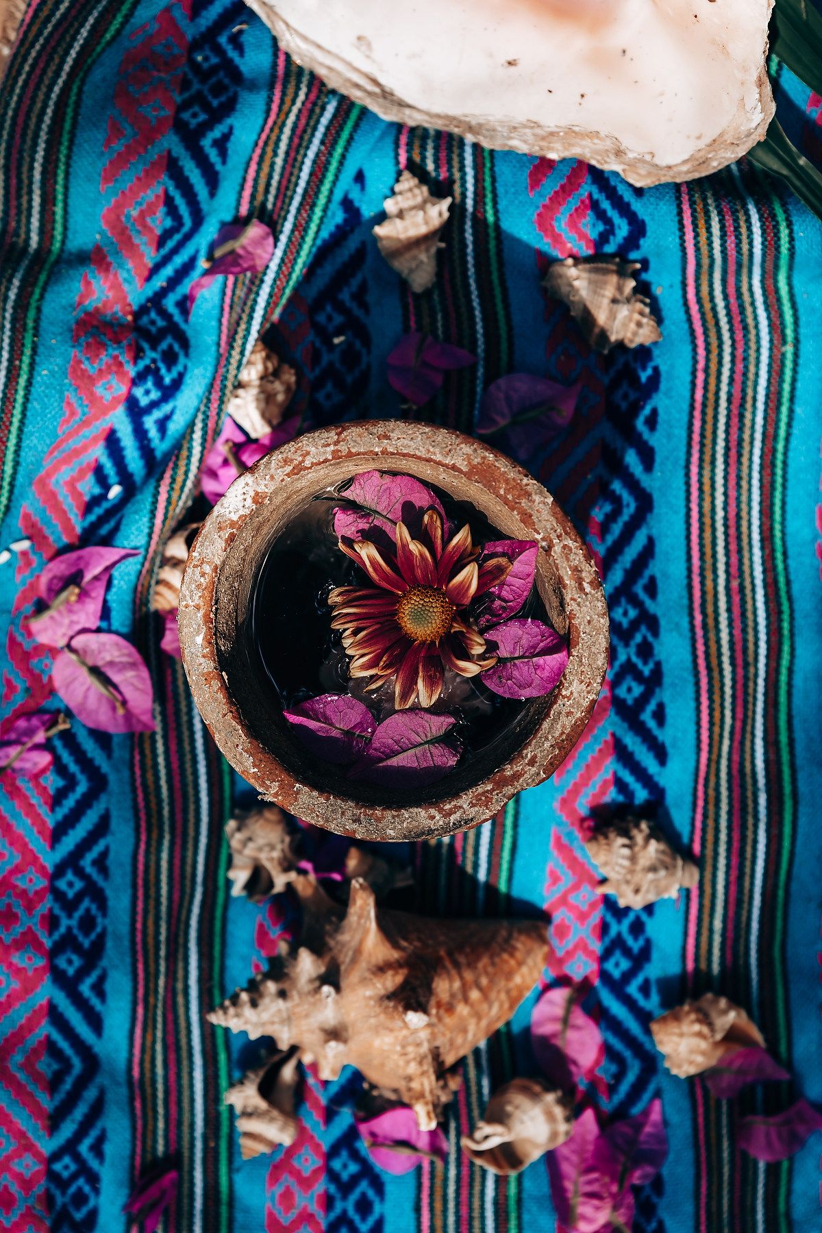Decorative straw hats with purple flowers mounted on a striped blue and black patterned fabric wall display.
