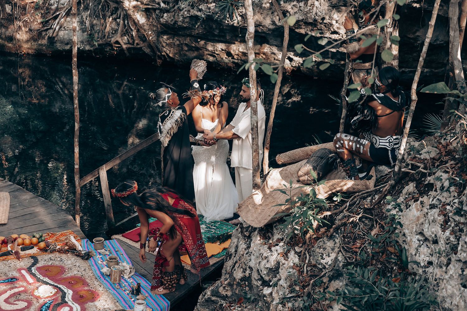 A wedding ceremony takes place in a cave setting with colorful rugs and decorative elements.