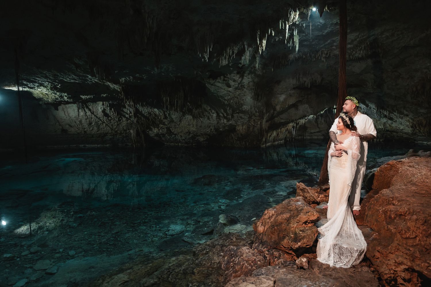 Ethereal wedding photos in a dramatic cave with turquoise water and rocky formations.