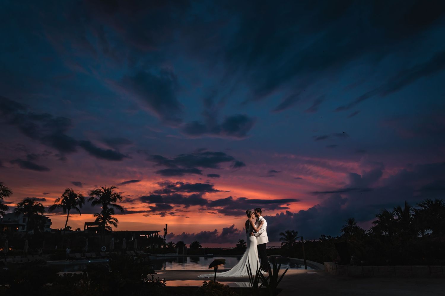 Panoramic sunset silhouette of wedding couple against colorful evening sky.