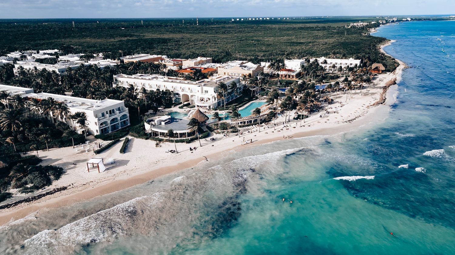 Aerial view of coastal resort with turquoise waters and white sandy beaches.