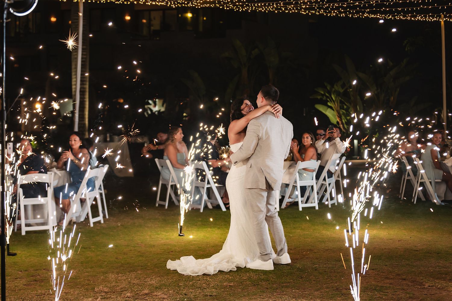 Wedding couple shares their first dance under twinkling lights and sparklers.