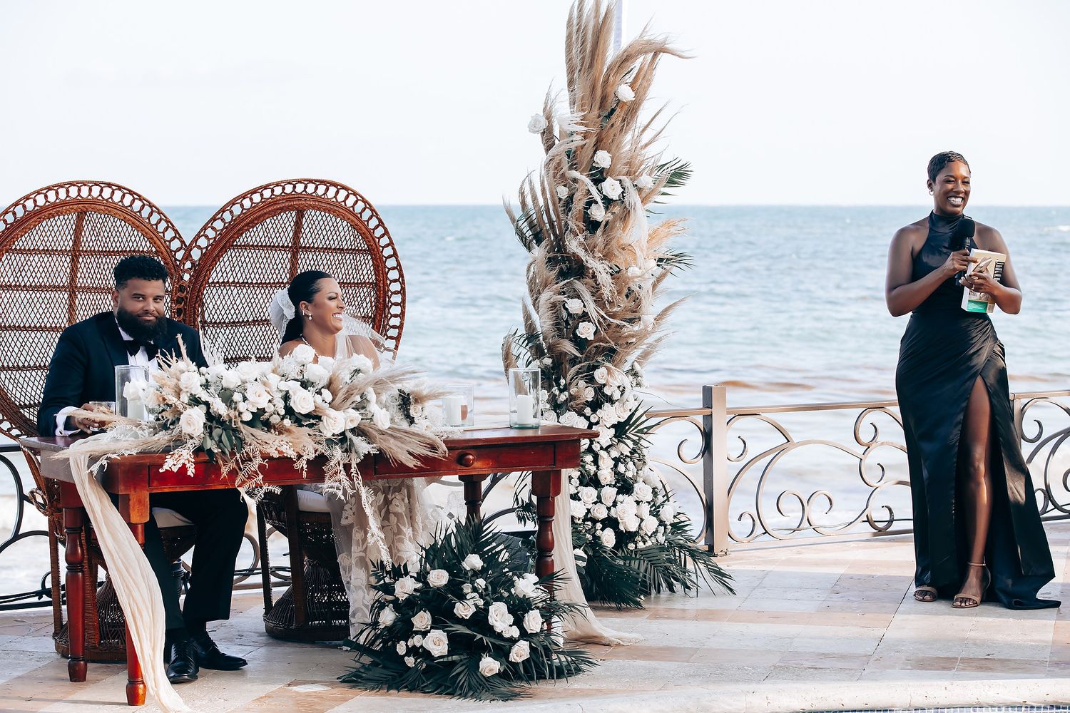 Seaside wedding ceremony space with ornate arches and tropical floral arrangements.