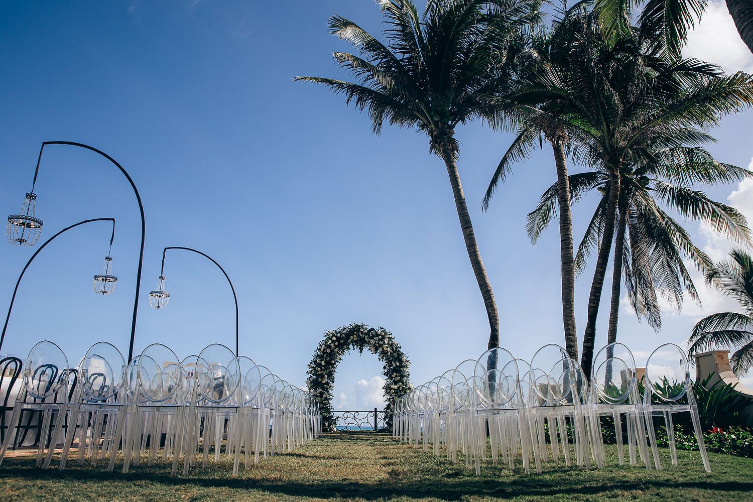 Palm trees line a beachfront path under blue skies at a tropical wedding venue.