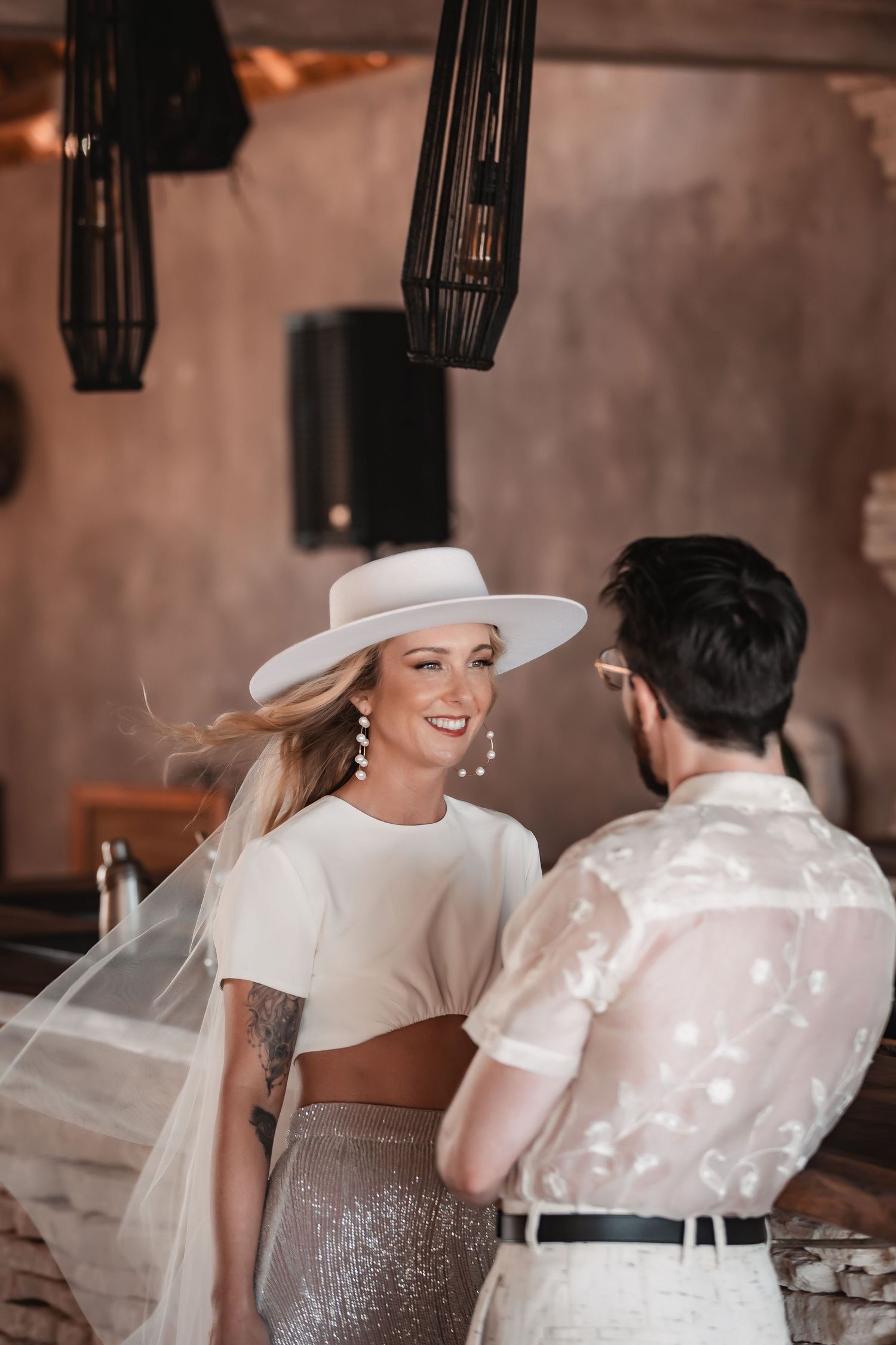 Wedding couple sharing an intimate moment in an industrial-style venue with pendant lighting.