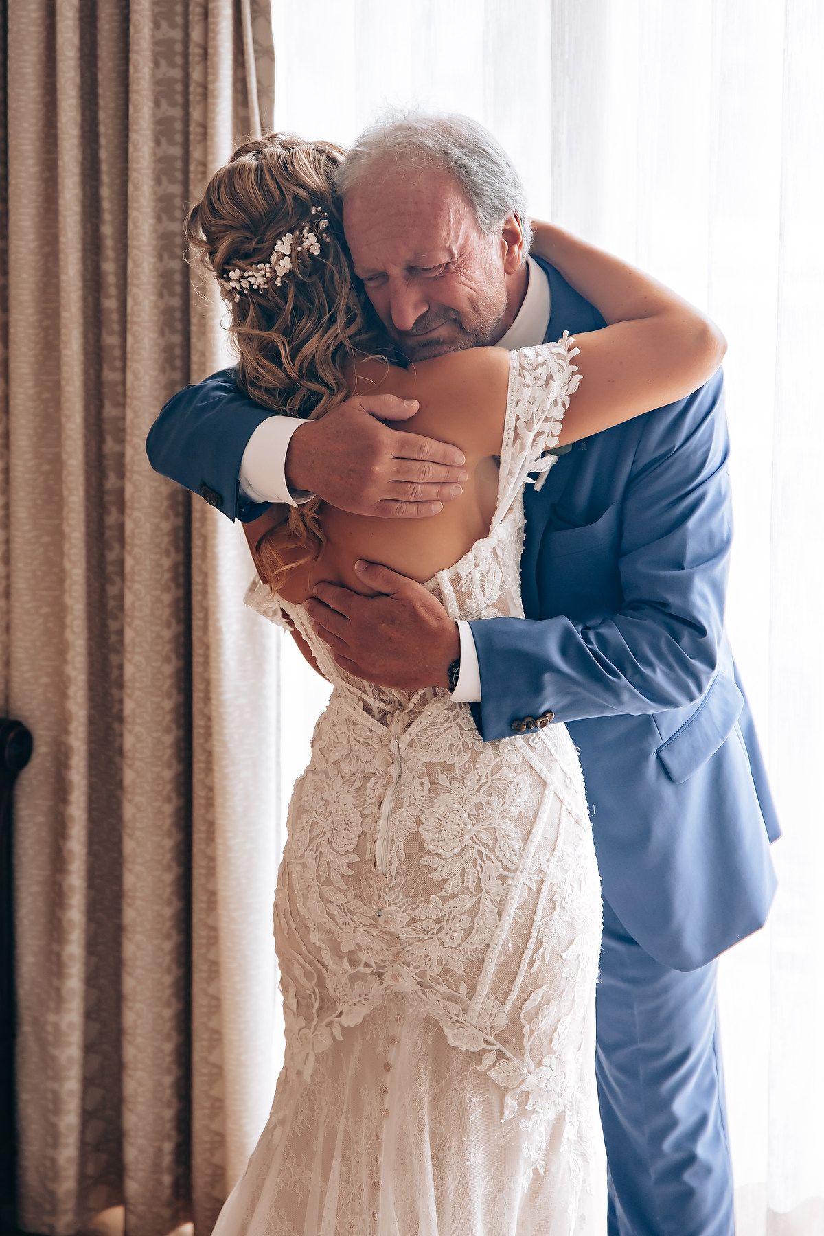 Emotional first look moment between father and bride in a lace wedding gown.