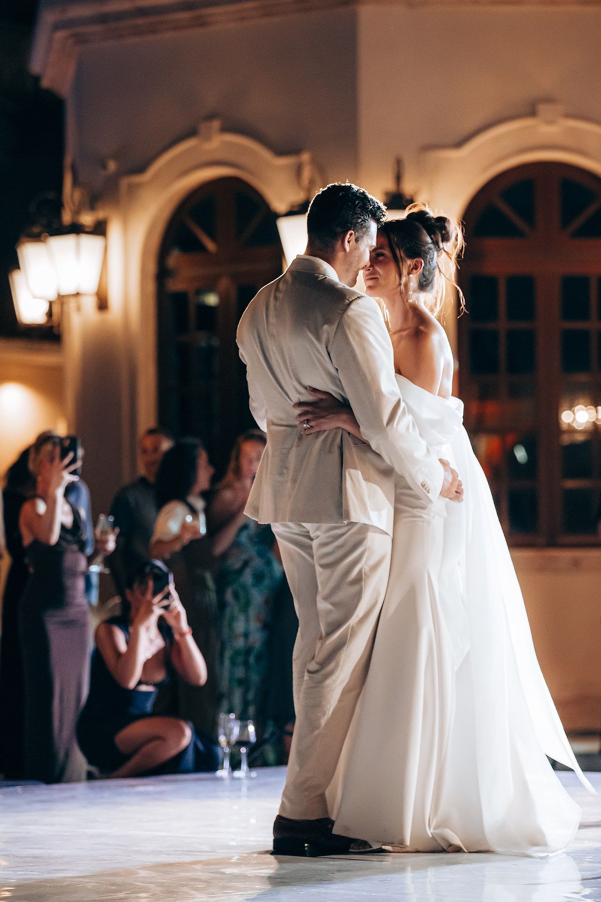 First dance at wedding reception with soft lighting and guests watching.