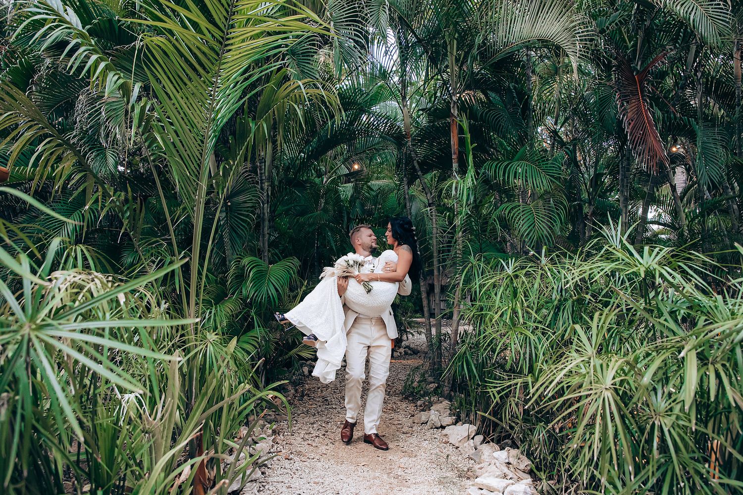 Bride and groom walking through palm garden at Mahekal Beach Resort