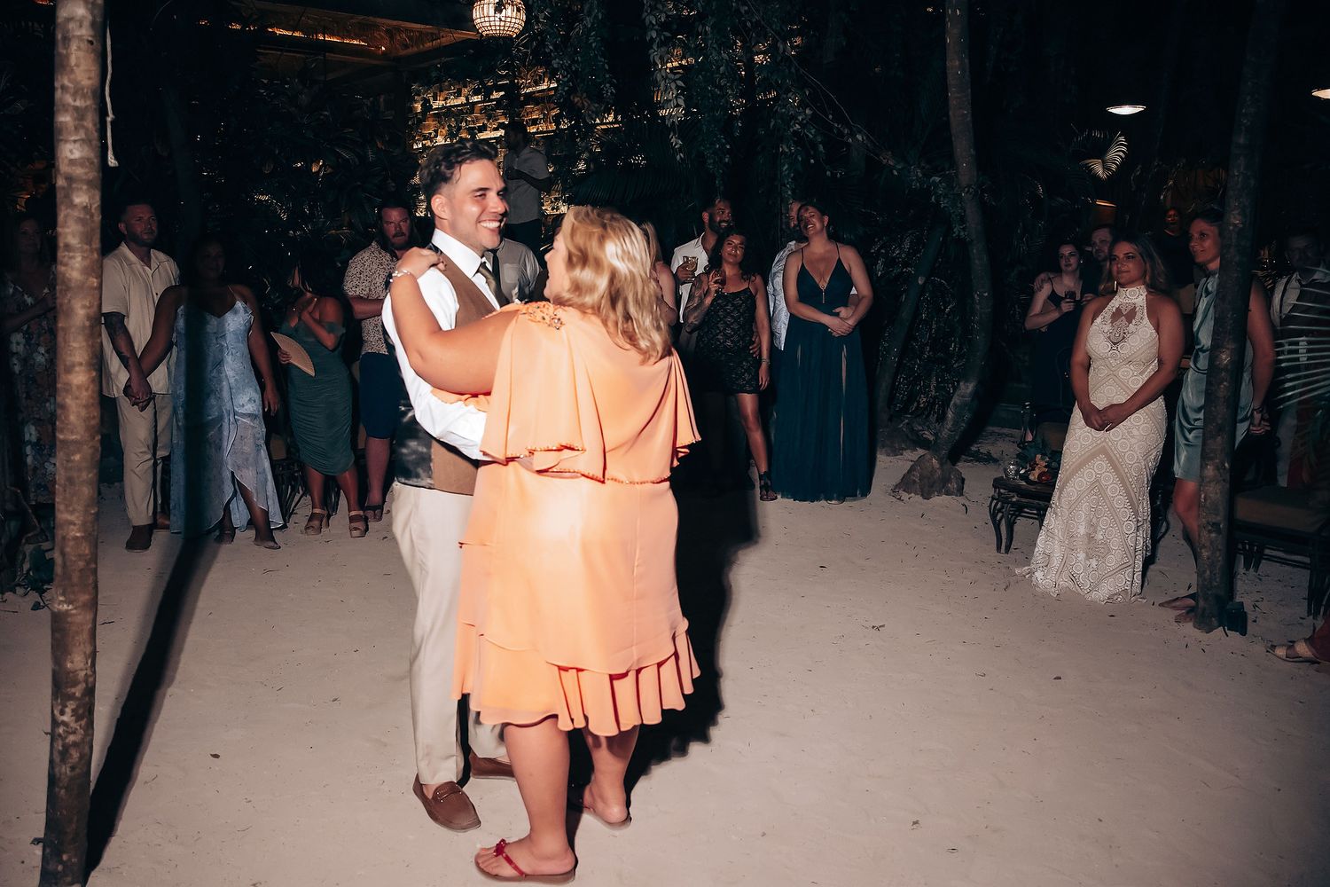 Dancers in formal attire twirl on a dimly lit dance floor at an elegant evening event.
