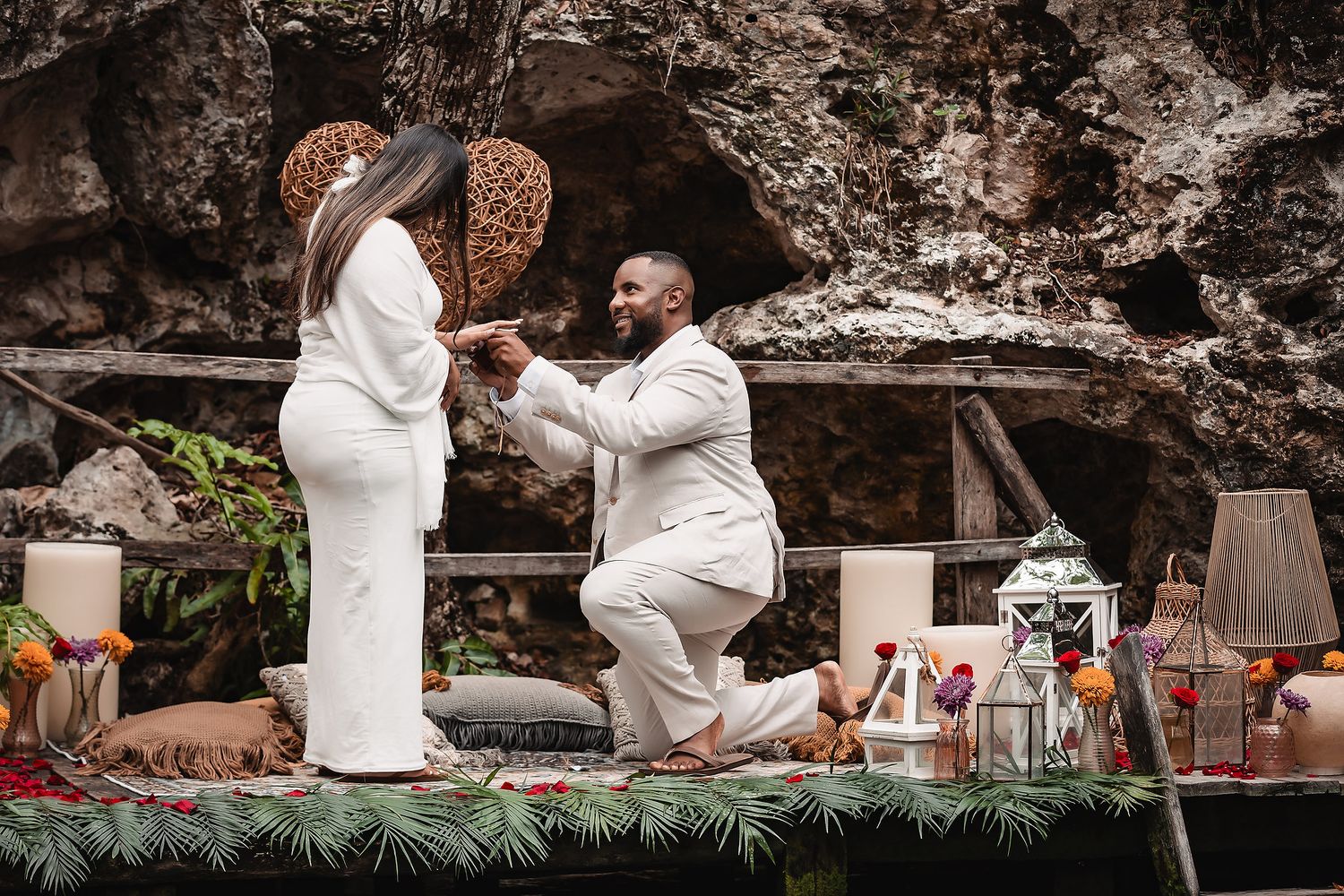 Special moment during proposal on decorated platform with lanterns and greenery in cave setting.