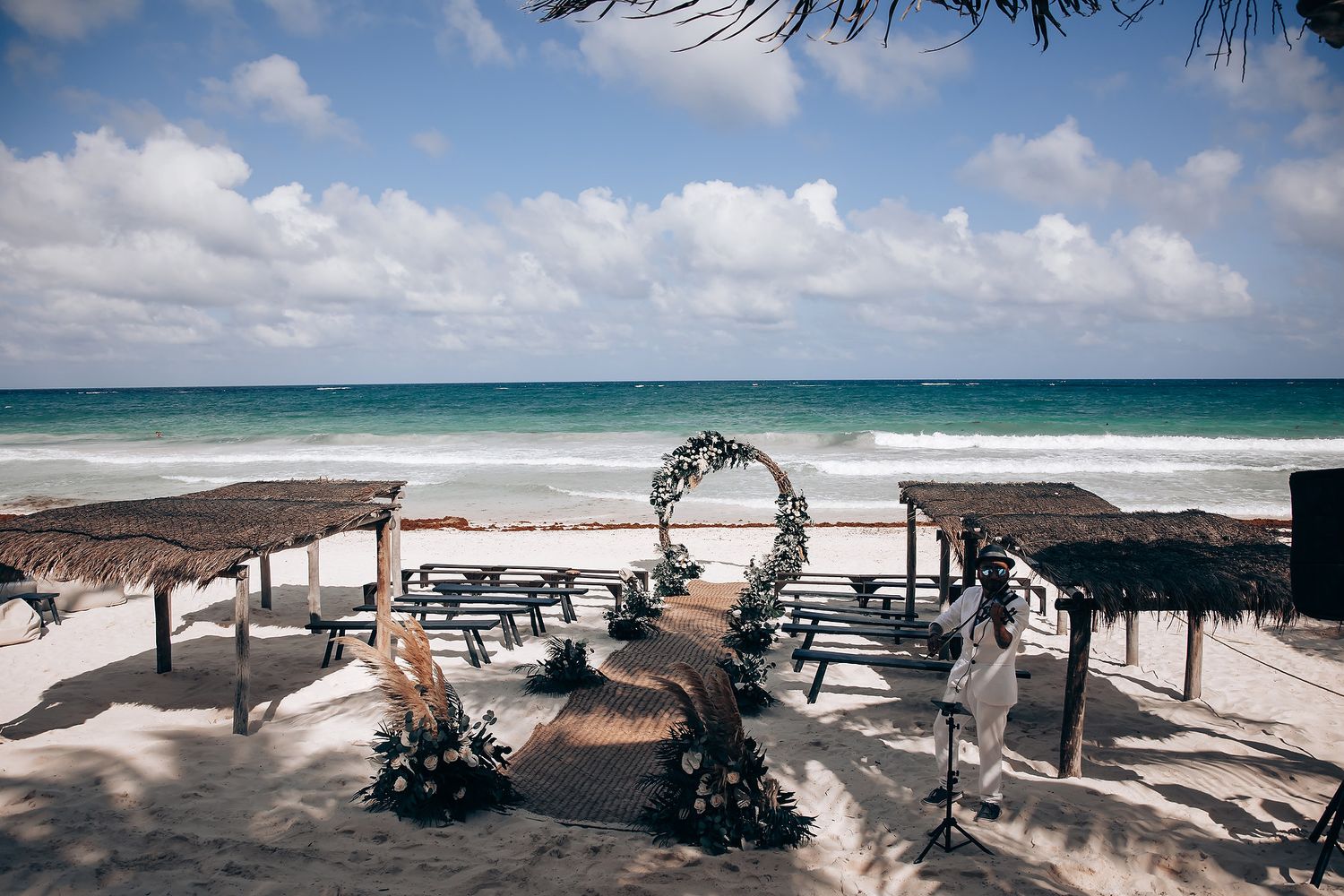 Beachfront wedding venue setup with rustic decor and natural tropical landscaping.