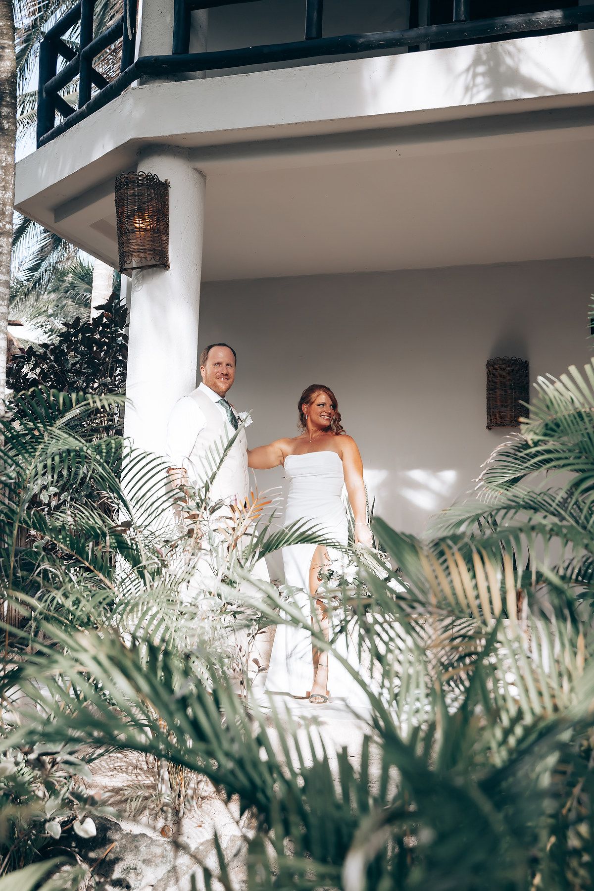 Tropical resort balcony with white architecture and lush palm gardens below.