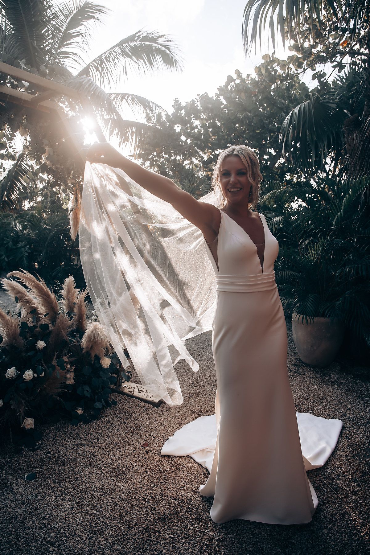 Ethereal wedding moment captured with sunlight streaming through palm trees.