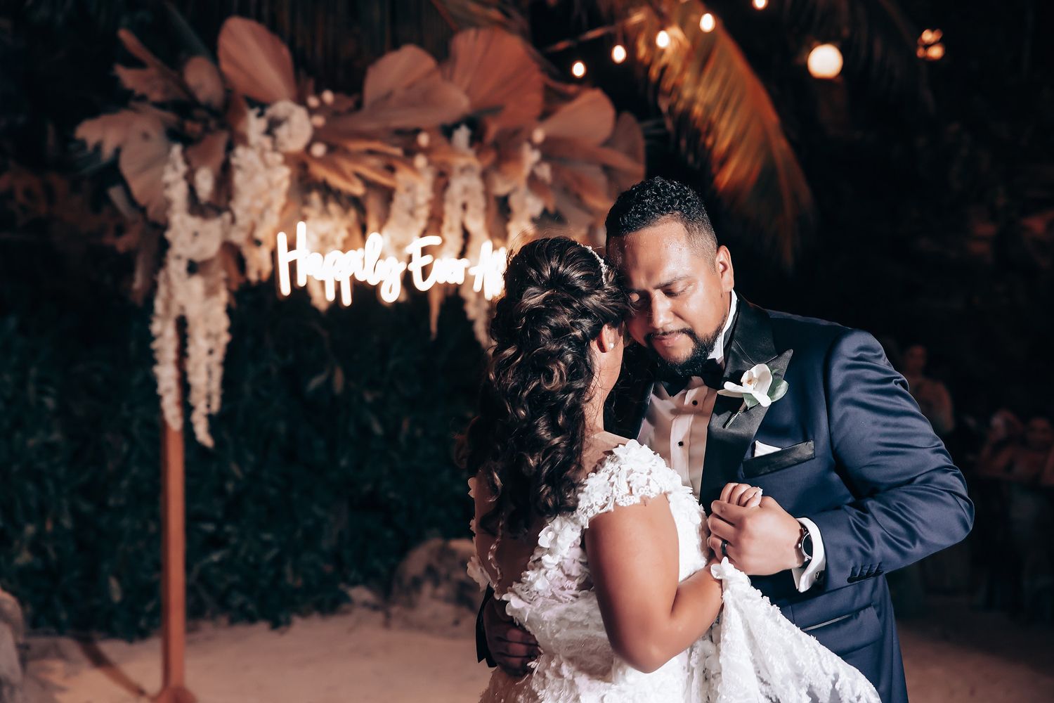 Romantic dance moment captured under twinkling lights at an evening wedding reception.
