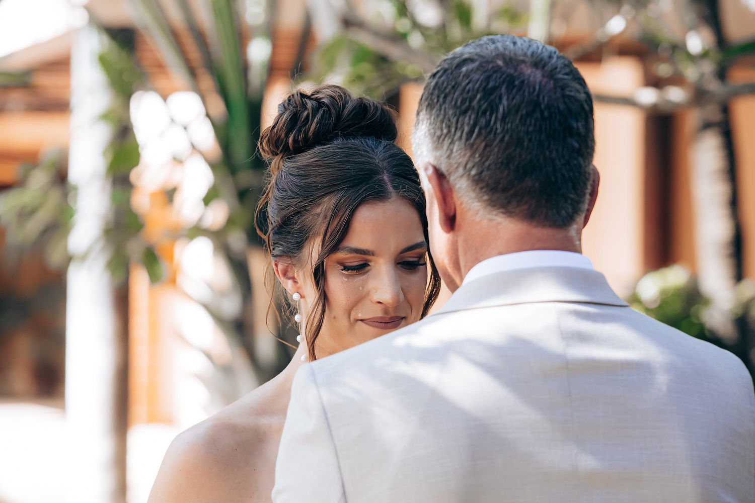 A couple shares an intimate moment during their outdoor wedding ceremony in a garden setting.