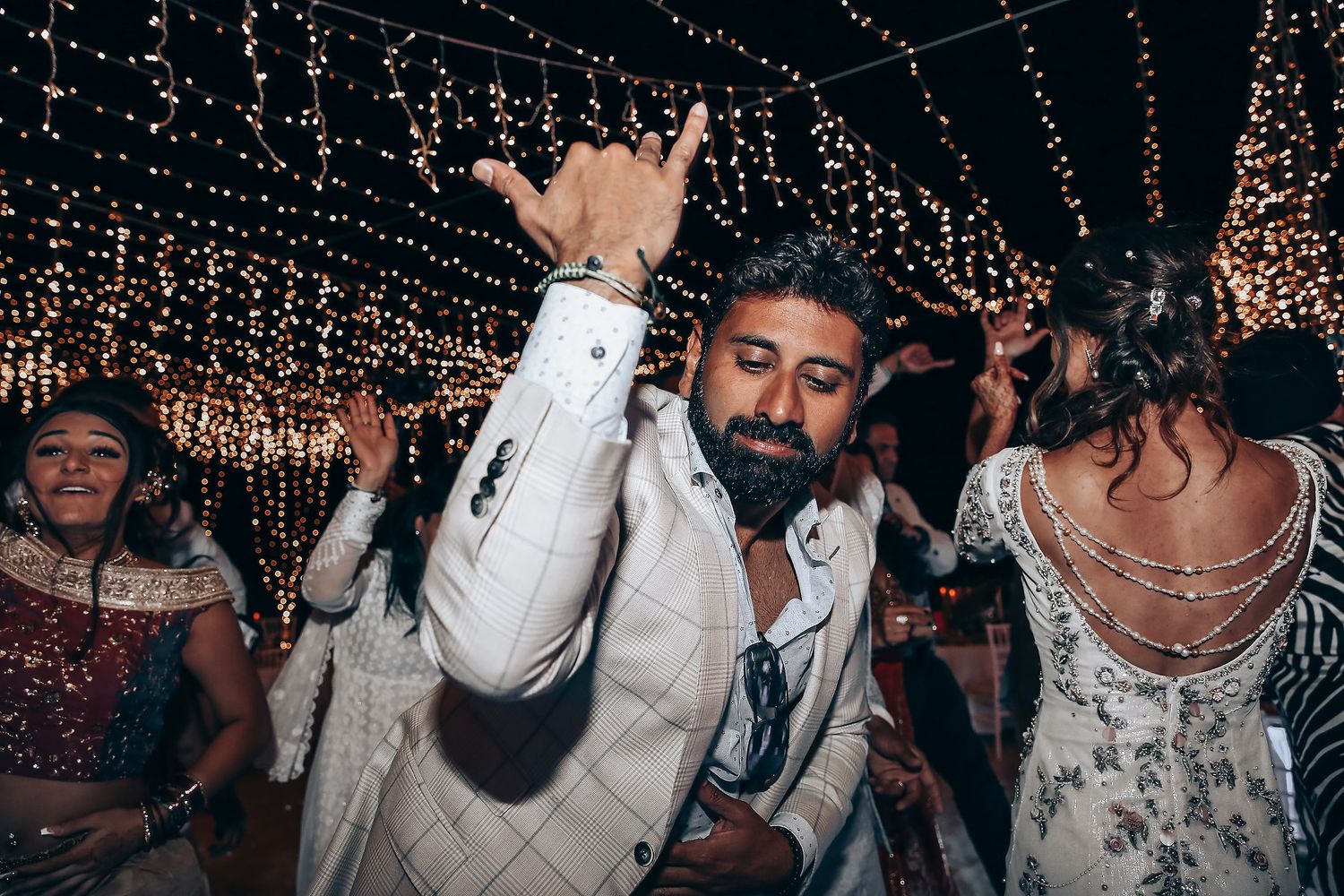 A lively dance party scene with people dancing under twinkling string lights and decorations.