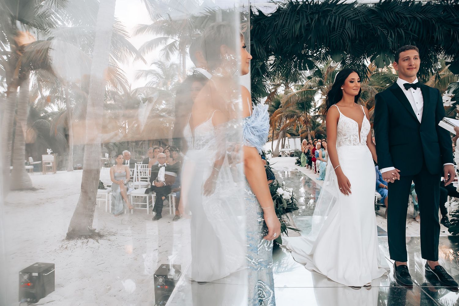 Wedding celebration in progress with guests mingling under a tropical palm setting.