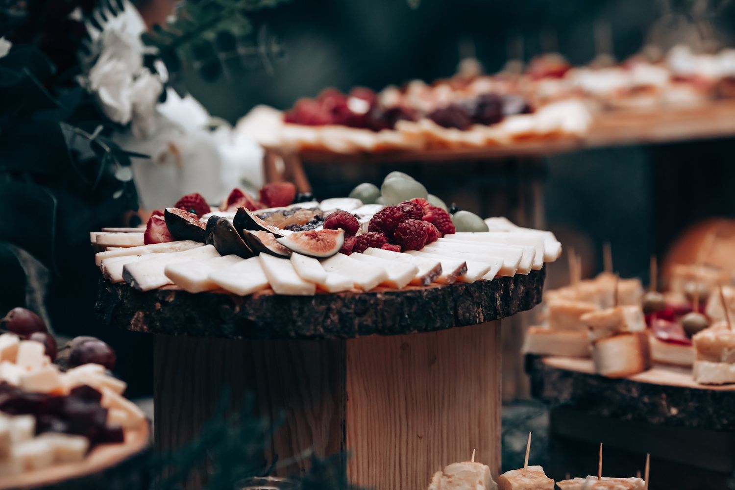 A variety of desserts and pastries displayed on a wooden buffet table with dark lighting and selective focus.