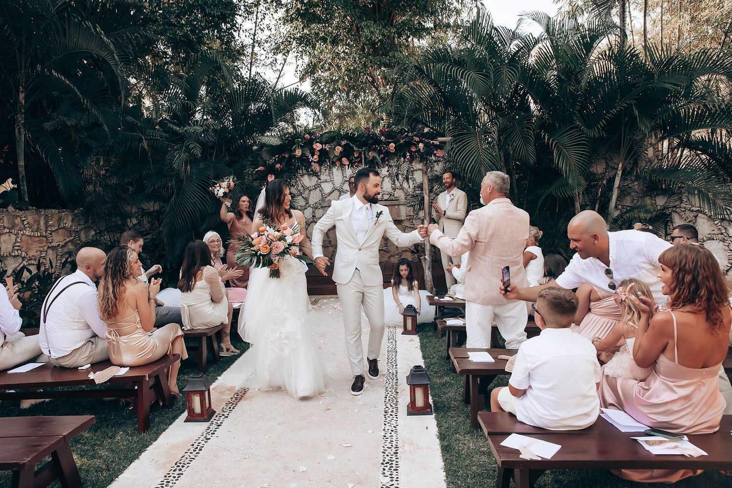 Wedding guests enjoying an outdoor reception under trees with string lights.