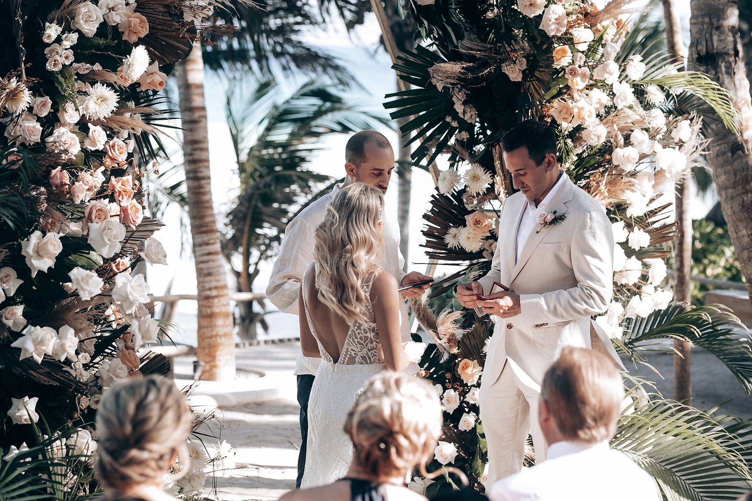 Elegant beach wedding ceremony setup with tropical palm trees and floral decorations.