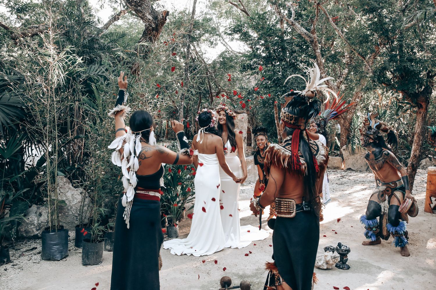 Wedding attendees celebrate in a serene woodland setting decorated with white fabric and natural elements.