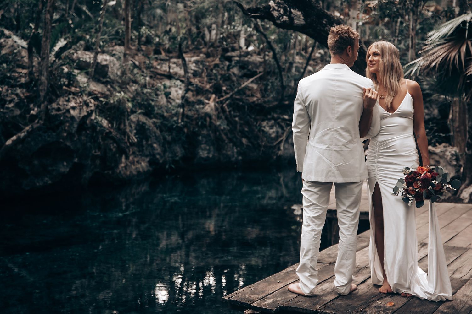 Wedding ceremony in progress on wooden platforms inside a dramatic cave environment.