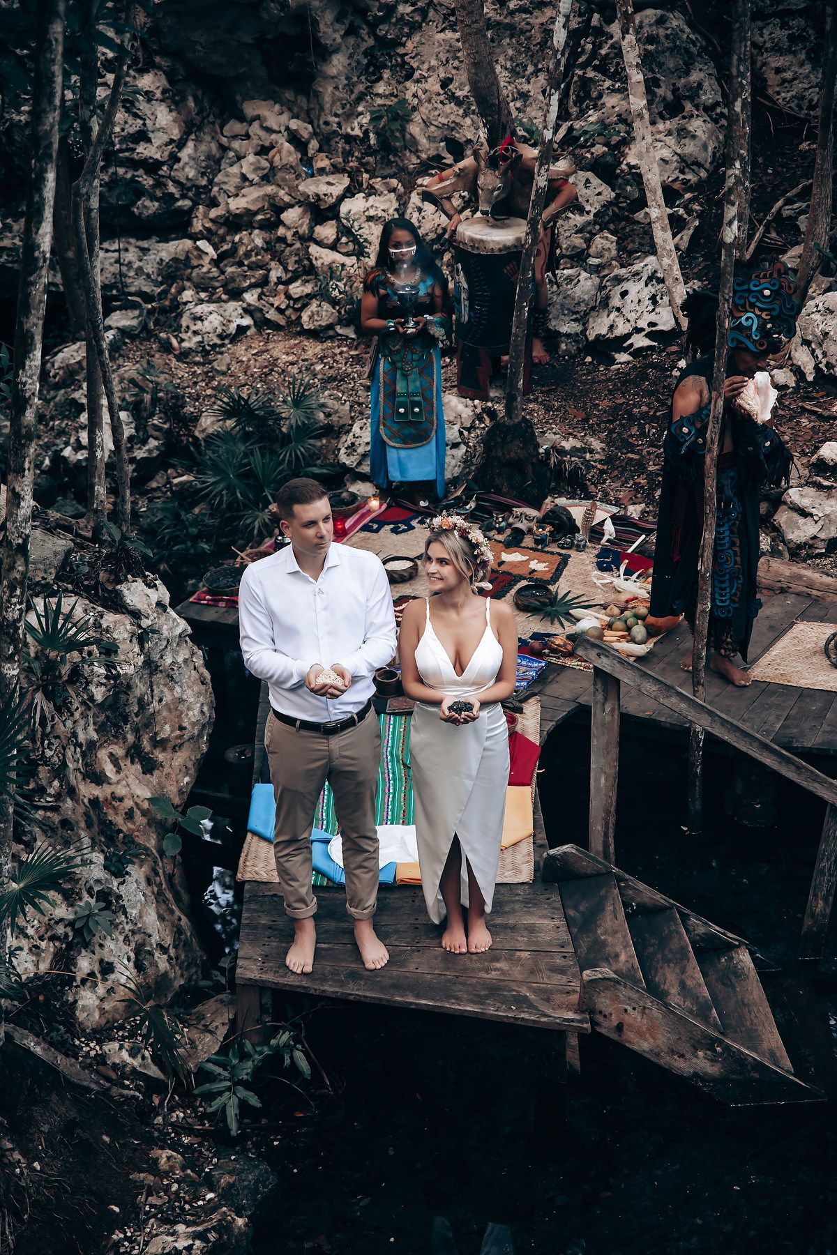 Romantic outdoor photoshoot on a wooden platform against weathered stone wall backdrop.