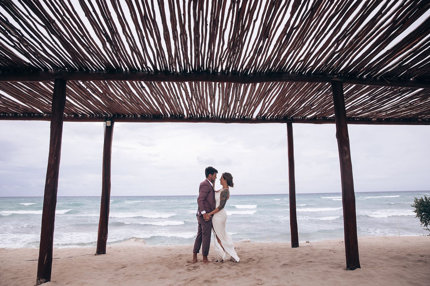 Silhouettes of palm trees create a natural canopy over a beach walkway.