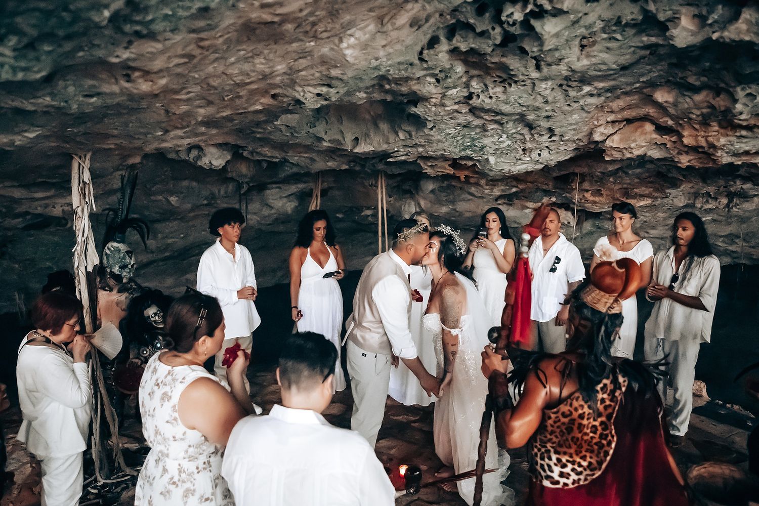 Wedding party gathered in a cave setting with decorative macrame backdrop.