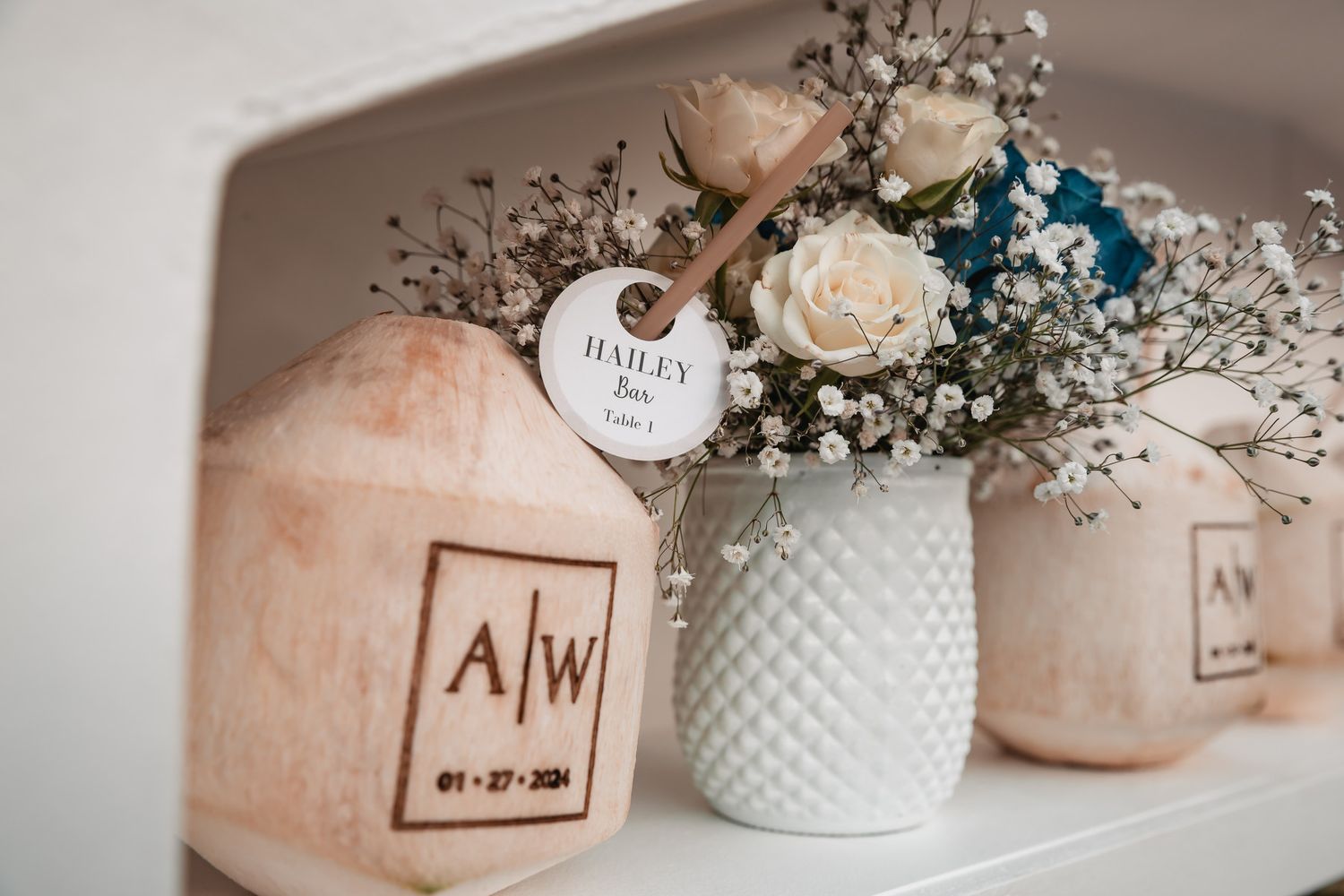 Wedding personalized coconut drinks with monogram AW and date displayed with white floral arrangement.
