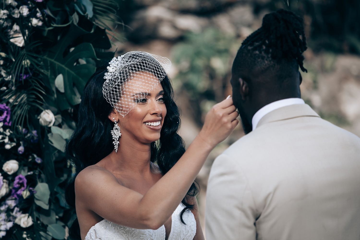 Wedding couple sharing intimate moment during outdoor ceremony with floral decorations.