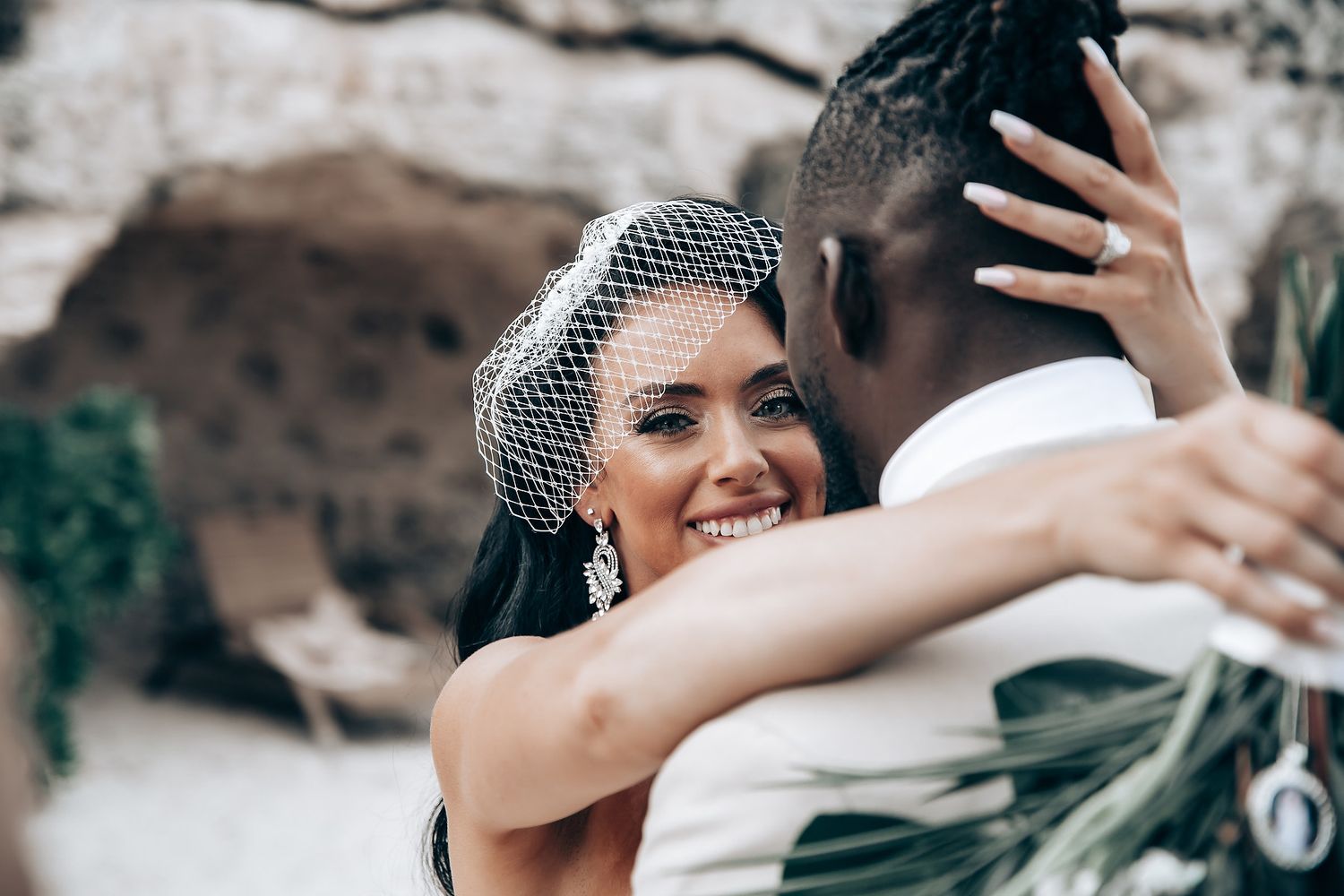 Intimate wedding moment captured against rocky cave backdrop.