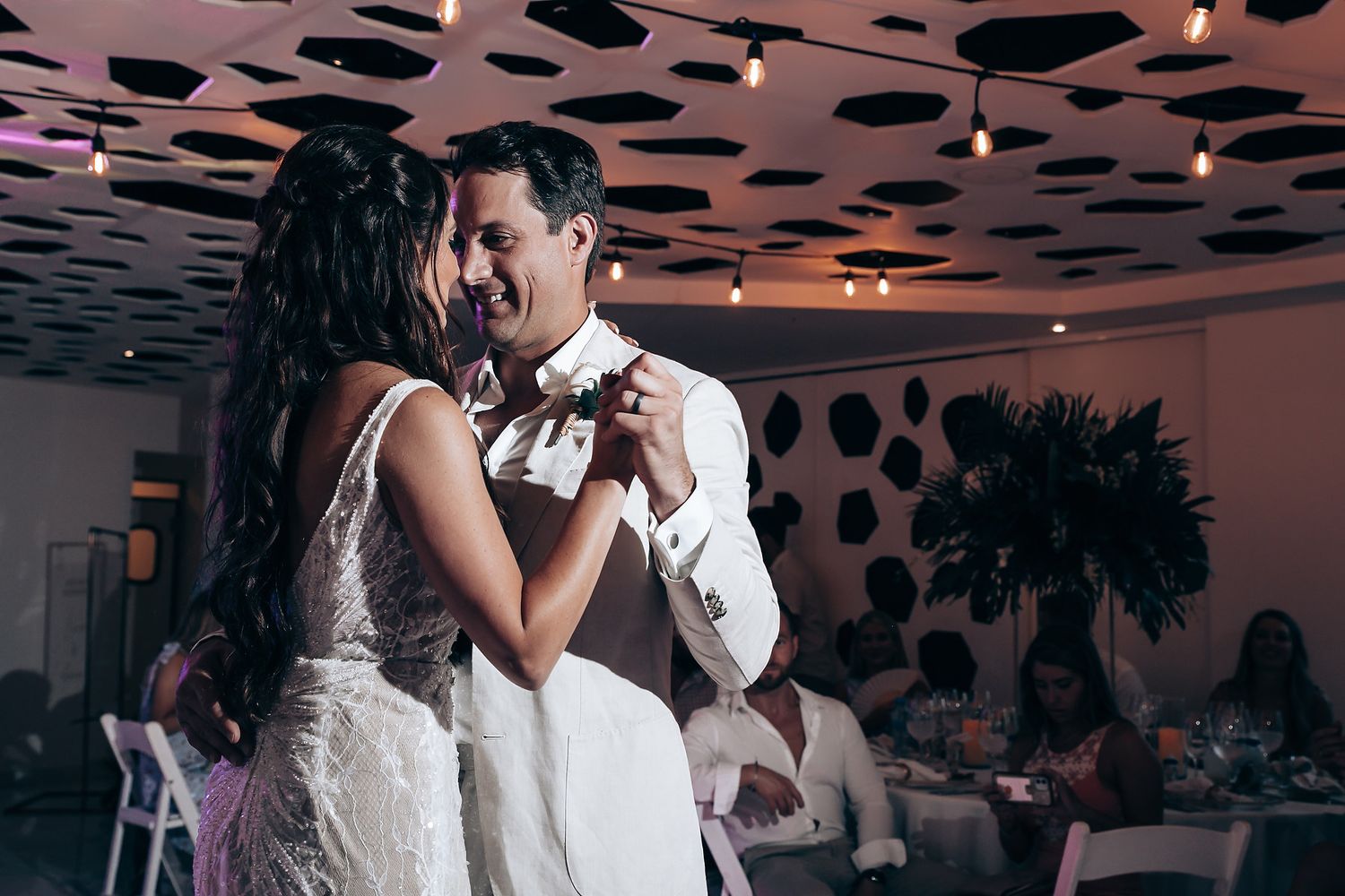 Couple sharing intimate dance moment under decorative spotted ceiling design.