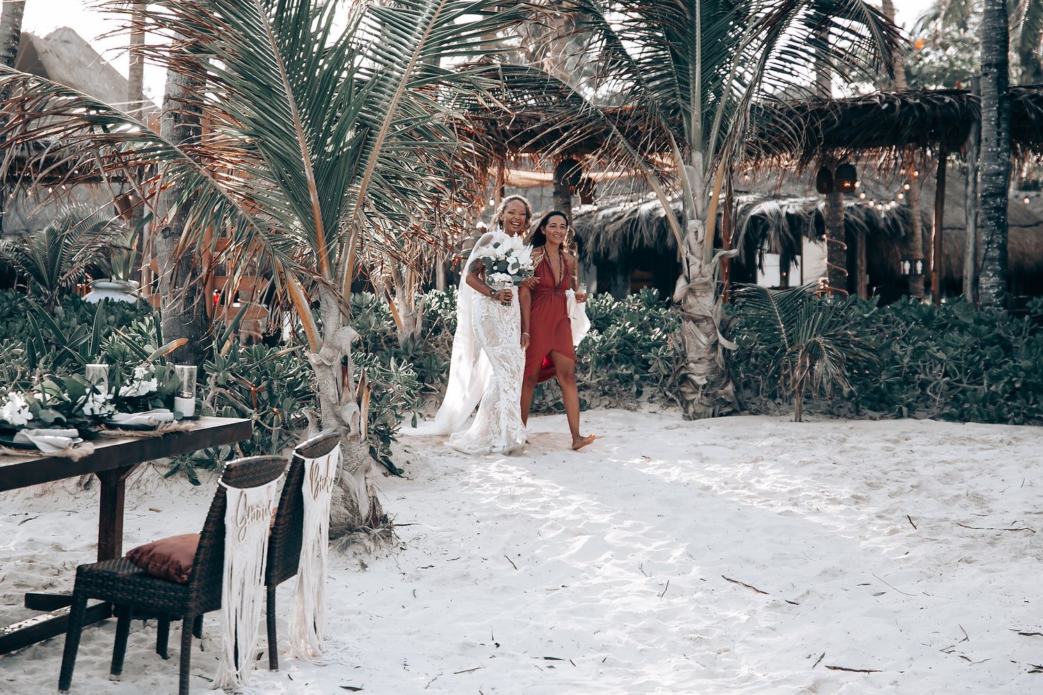 Tropical beach wedding venue with palm trees and white chairs arranged for ceremony.