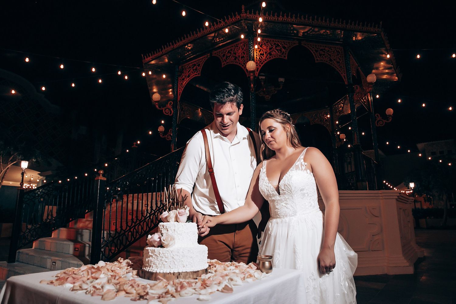 Wedding couple shares an intimate moment while cutting their cake at a romantic evening reception.