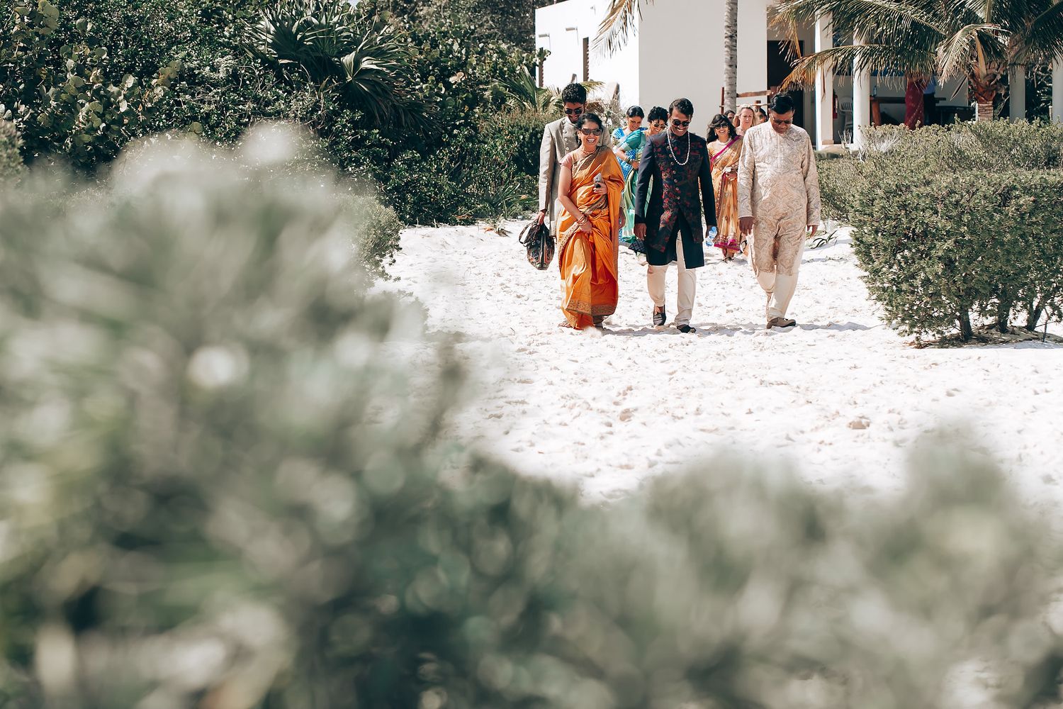Wedding guests walking through a garden path during an outdoor ceremony.