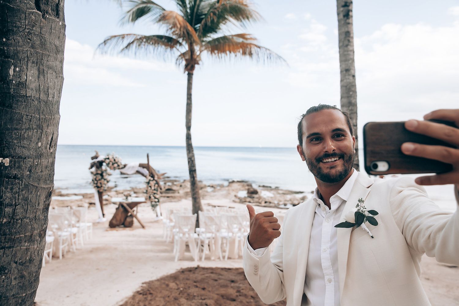 Tropical beach wedding ceremony setup with palm trees and ocean views.